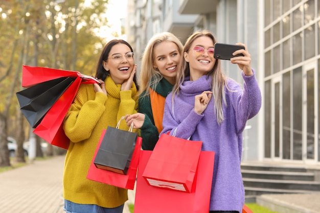 Belles jeunes femmes prenant selfie à l'extérieur après le shopping