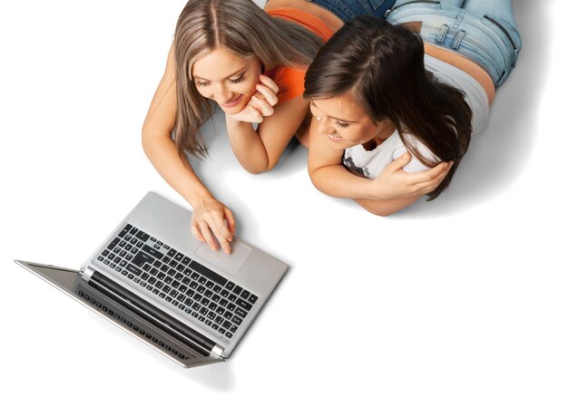 Belles jeunes filles utilisant un ordinateur portable pendant la pose, isolées sur blanc