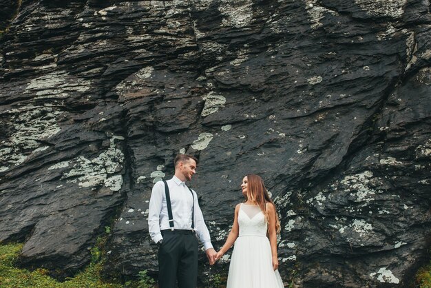 Belles jeunes mariés le jour de leur mariage posant sur un fond de pierre Voyage de mariage de paysage de montagne