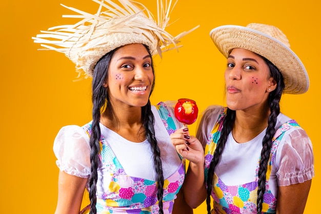 Belles jumelles en vêtements de fête de juin mangeant une pomme d'amour