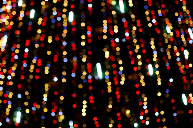 Photo de belles lumières de noël multicolores sur un fond noir fond abstrait festif