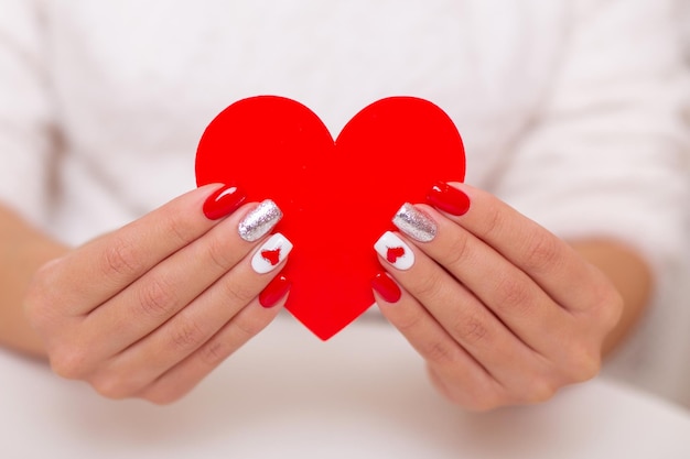 Belles mains féminines avec conception de coeurs ongles manucure rouge sur fond blanc