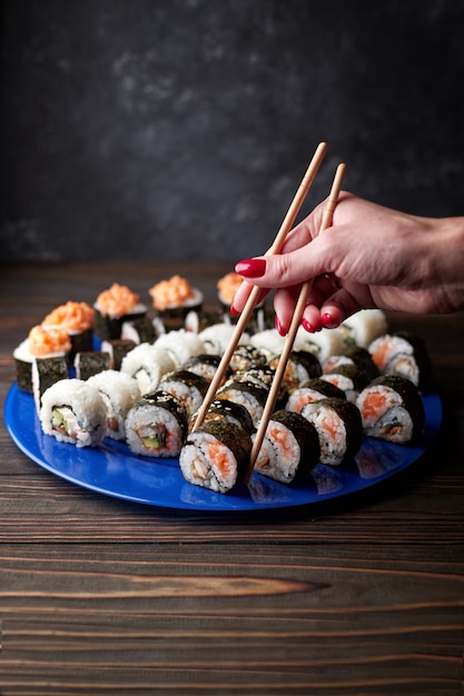 Belles mains féminines prennent des sushis avec des baguettes.