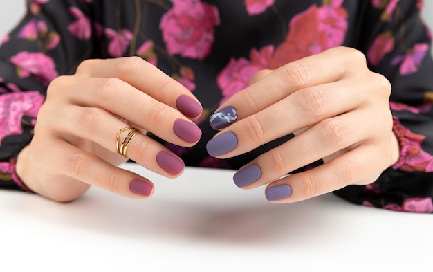 Belles mains de femme avec manucure mate bordeaux violet