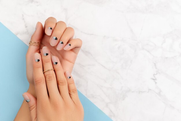 Belles mains de femme soignées avec un design d'ongles mat nude et bleu