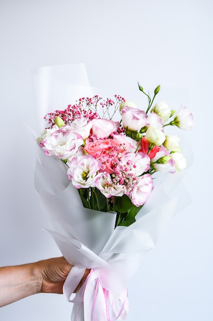 Belles mains de femme tiennent le bouquet de différentes fleurs blanches et violettes sur fond blanc. Personne. Sans visage