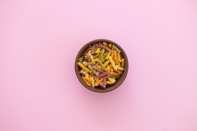 Belles pâtes farfalle colorées non cuites italiennes gros plan sur fond rose vue de dessus horizontale