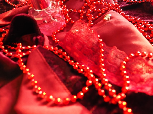 Belles perles rouges sur velours écarlate brillant Beaux bijoux luxueux pour femmes sur tissu doux Gros plan à plat Trucs et cosmétiques pour femmes Articles en arrière-plan Flou artistique défocalisé