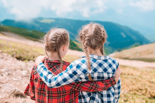 Photo belles petites filles heureuse dans les montagnes en arrière-plan du brouillard