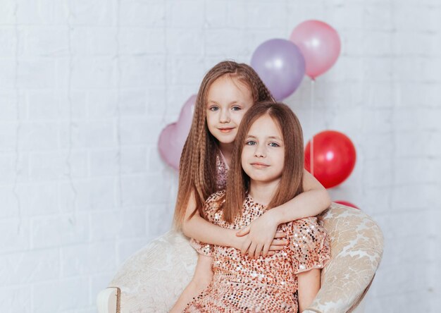 Belles petites soeurs filles plaisantant à la fête d'anniversaire jeunes filles avec des ballons se préparant pour les fêtes