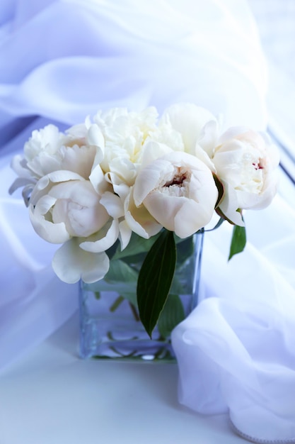 Belles pivoines blanches dans un vase sur fond de tissu