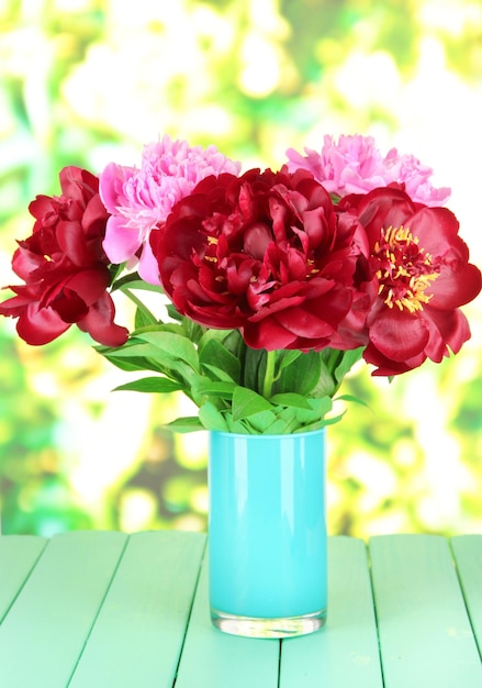 Belles pivoines dans un vase sur table sur fond clair