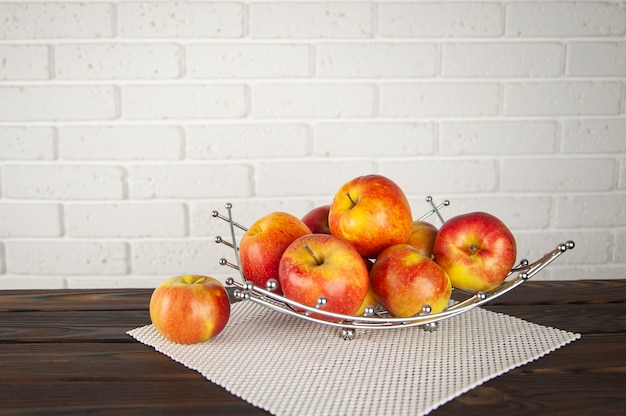 Belles pommes dans un bol de fruits sur une surface en bois