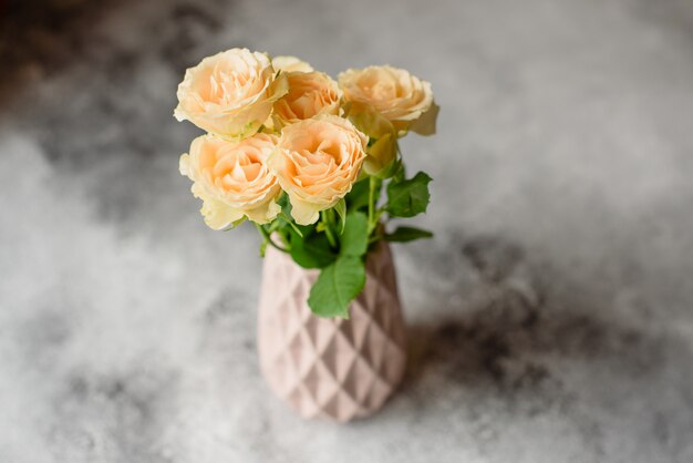 Belles roses beiges fraîches dans un vase d&#39;argile sur un fond de béton. Pose et décoration d&#39;une table