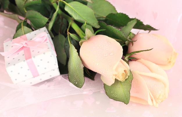 Belles roses et cadeau sur tissu rose, gros plan