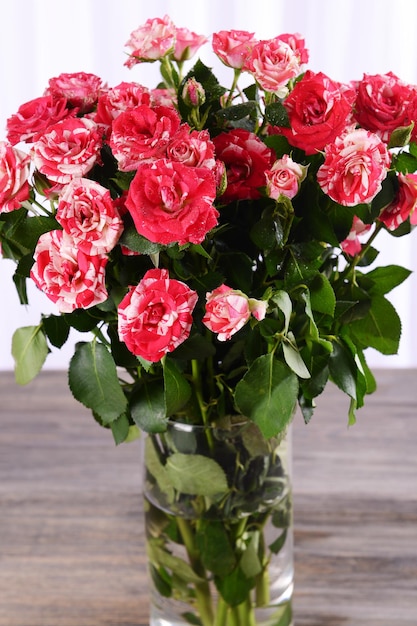 Belles roses dans un vase sur table sur fond clair