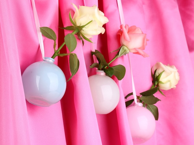 Belles roses dans des vases suspendus à un tissu