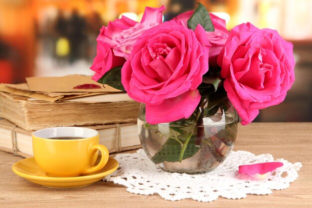 Belles roses roses dans un vase sur une table en bois sur fond de chambre