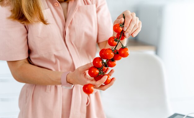 Belles tomates rouges sur une branche en mains.