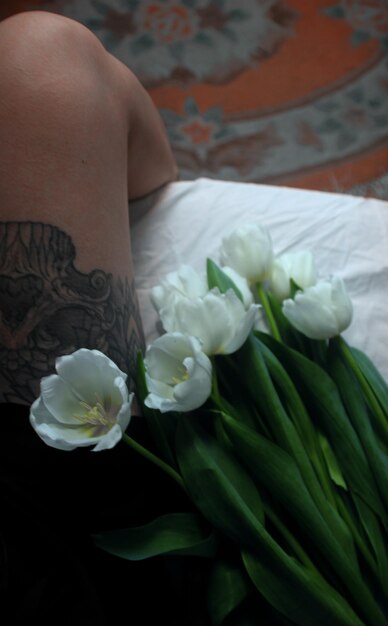 Belles tulipes blanches se trouvent sur un couvre-lit blanc tapis de grand-mère tatouage noir sur le le de la fille