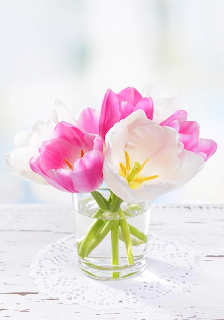 Belles tulipes dans un seau dans un vase sur une table sur fond clair