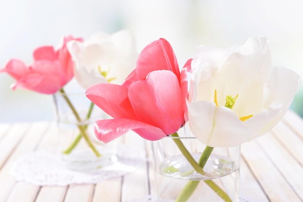 Belles tulipes dans un seau dans un vase sur une table sur fond clair