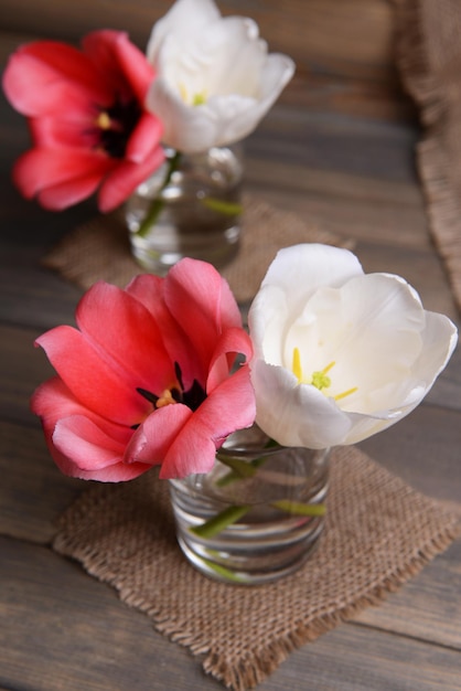 Belles tulipes dans un seau dans un vase sur une table sur fond gris