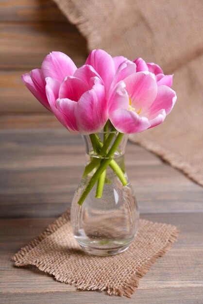 Belles tulipes dans un seau dans un vase sur une table sur fond gris