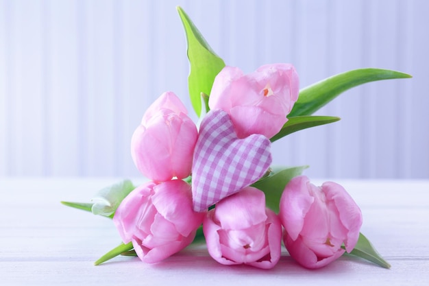 Belles tulipes roses avec coeur décoratif sur fond en bois