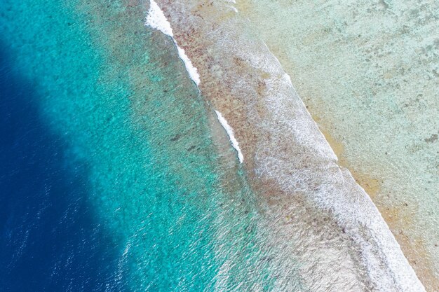 Belles vagues de la mer blanche tropicale vues d'en haut sur le lagon de l'océan bleu de la côte rocheuse des récifs coralliens