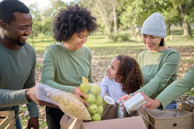 Photo bénévolat de dons alimentaires et personnes avec enfant pour la durabilité aide à la pauvreté et service communautaire dans le parc soutenir le travail d'équipe et les fruits légumes et boîte pour les sans-abri caritatifs ou les soins de la société