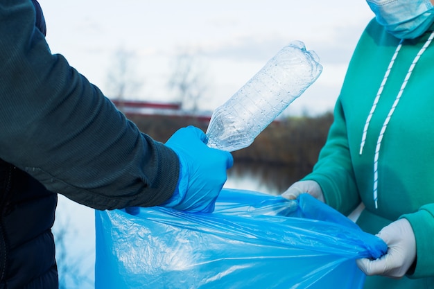 Les bénévoles collectent des bouteilles en plastique dans des sacs, gros plan des mains, le concept d'écologie et de protection de la terre.