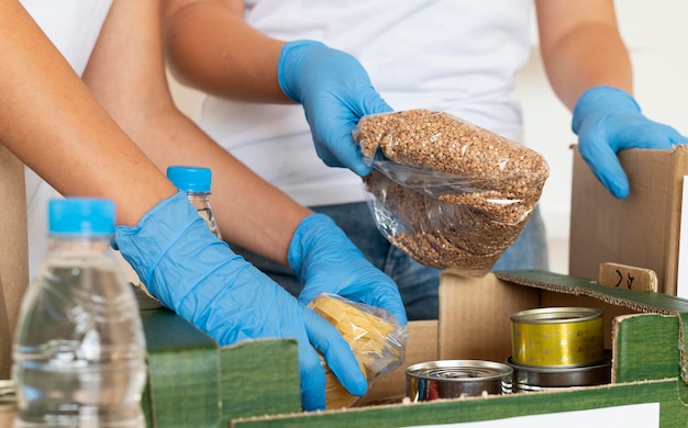 Des bénévoles avec des gants préparant des caisses de dons alimentaires