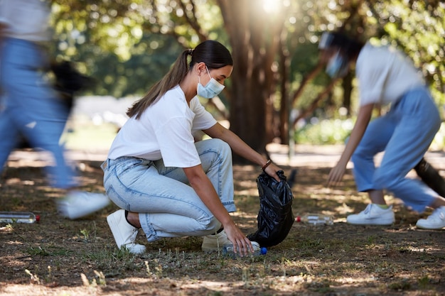 Des bénévoles recyclent et réduisent les déchets en ramassant la saleté et les ordures à l'extérieur dans un parc pendant le covid Une jeune équipe de militantes d'ONG nettoyant l'environnement pendant la pandémie de covid19