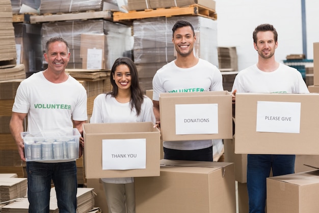 Bénévoles souriant à la caméra tenant des boîtes de dons