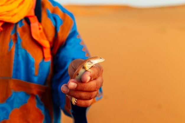 Photo berbère en costume traditionnel tient une salamandre à la main.