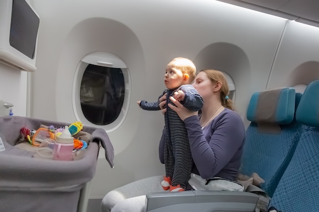 Berceau spécial pour bébé pendant le vol Premier vol de la mère d'une petite fille tient le bébé dans les bras dans l'avion