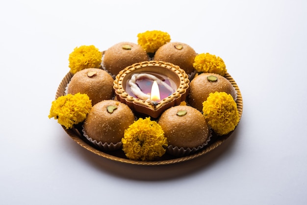 Besan ladoo et diwali diya ou lampe en argile décorée dans une assiette de fleurs de souci - Happy Diwali Greeting