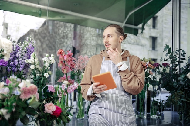 Besoin de penser. Beau jeune homme s'appuyant sur la table et créant le futur ikebana