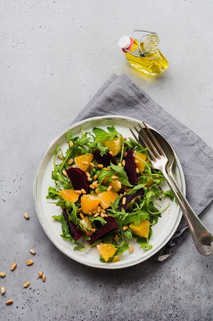 Betteraves, orange, pignon de pin, huile d'olive, fromage feta et salade de roquette en plaque en céramique sur la vieille table en béton