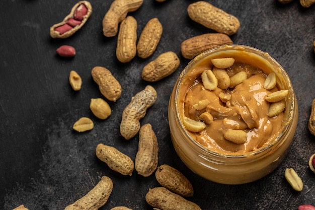 Beurre d'arachide dans un bocal en verre et une cuillère sur fond gris concept de dessert américain vue de dessus place pour le texte