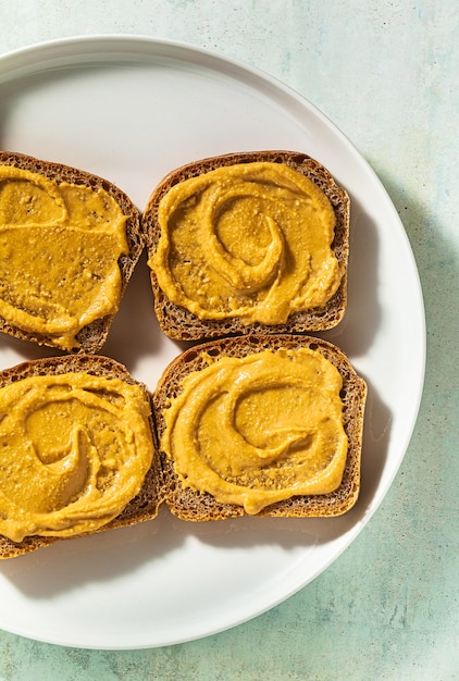 Beurre d'arachide tartiné sur du pain et un couteau sur une assiette sur la table