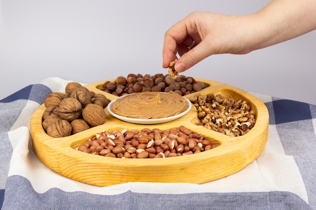 Beurre de cacahuète crémeux beurre de cacahuète dans un bocal en verre ouvert au centre d'un fond de nourriture d'arachide Cacahuètes en coque cacahuètes pelées sur fond blanc Concept alimentaire végétalien