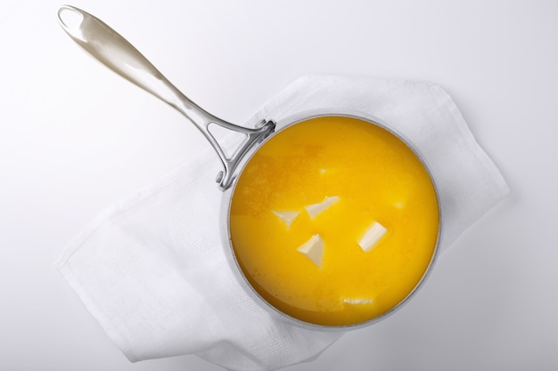 Beurre dans une casserole en métal pour la cuisson du ghee. Fond clair. Vue de dessus.