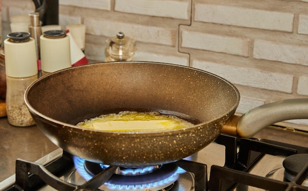 Le beurre est fondu dans une poêle à frire sur une cuisinière à gaz