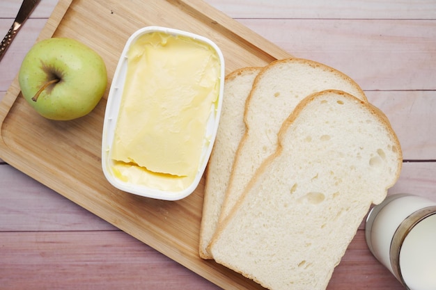 Beurre frais dans un récipient avec pomme à pain et lait sur table
