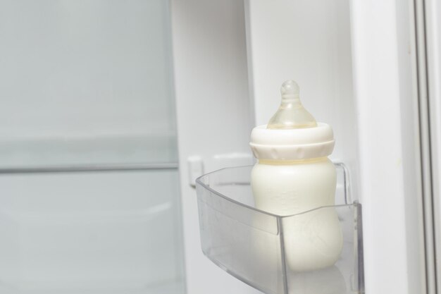 Photo biberon plein de lait dans la boîte de la porte du réfrigérateur