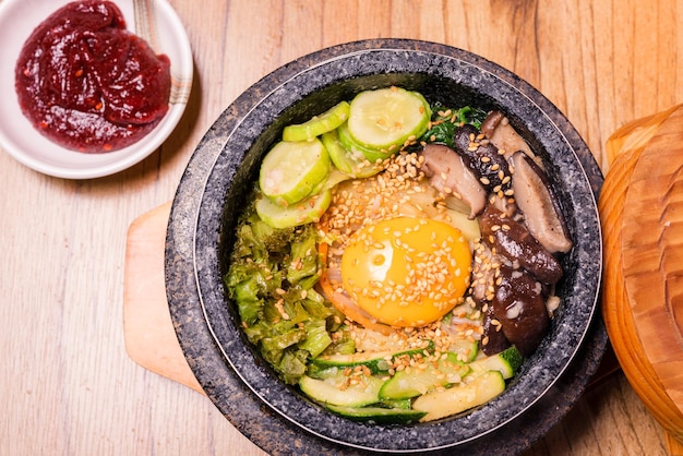 Bibimbap dans un bol en pierre noire chauffée plat traditionnel coréen bibimbap riz mélangé avec des légumes