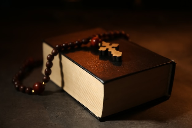 Bible avec chapelet sur table sombre