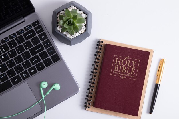 Bible et ordinateur portable sur la table de travail avec des écouteurs. Concept en ligne d'étude de la Bible